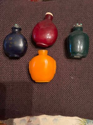 quatre bouteilles de couleurs différentes posées sur un coussin marron