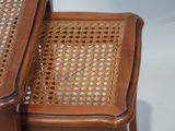 two wooden chairs with wicker seats and a cane back