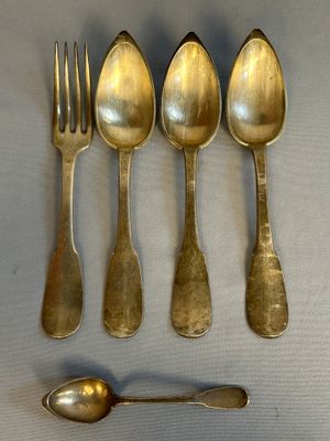 six spoons and a fork are arranged on a table