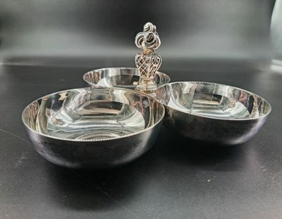 two silver bowls on a black table with a silver spoon