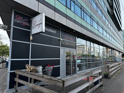 un banc en bois installé devant un restaurant, au bord de la rue