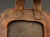 a brown leather bag with a picture frame on it