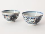 pair of blue and white bowls with floral designs on them on a white surface
