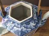 a blue and white tea pot and a cup on a table