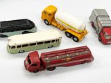 cinq camions miniatures et un bus posés sur une surface blanche