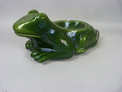 une figurine de grenouille verte posée sur une surface blanche