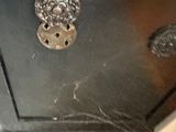 a close up of a black dresser with a spider web on it