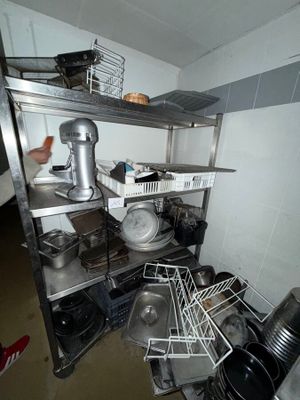 a man that is standing in a kitchen next to a shelf