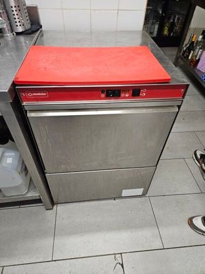 Une personne se tient dans une cuisine dont le plan de travail est rouge.