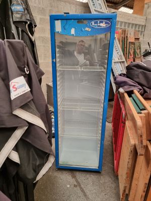 a blue refrigerator that is sitting in the middle of a pile of clothes