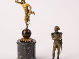statue of a man standing on a pedestal next to a statue of a man on a ball