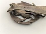 a silver brooch with a bird on it