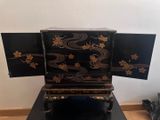 a black and gold chest of drawers on a black table