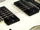 a close up of a white electric guitar on a table