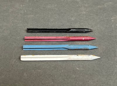 Quatre crayons de couleur différents sont alignés sur une table.