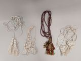 quatre colliers en macramé avec des pompons sur fond blanc