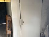 un réfrigérateur blanc dans un garage, avec une chaise en bois