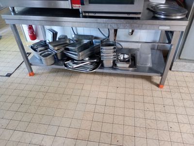 une étagère argentée sur laquelle sont posés des casseroles et des poêles