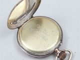 a small silver pocket watch with a key in it