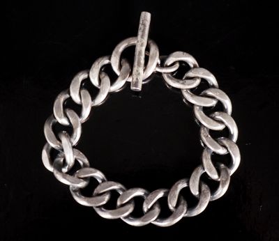 un gros plan d'un bracelet à chaîne argentée sur fond noir