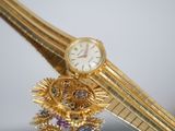 a gold watch sitting on top of a table next to a mirror