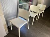 three white chairs sitting in front of a window
