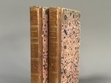 deux livres anciens posés l'un sur l'autre sur une surface grise
