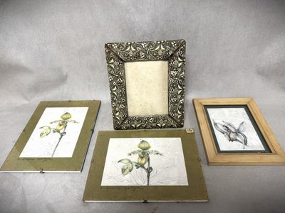 trois photos encadrées représentant des fleurs et un oiseau, posées sur une table