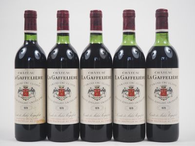 quatre bouteilles de vin rouge sont alignées sur une surface blanche