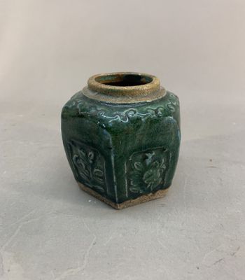 a green vase with a design on it on a white surface