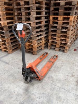 an orange forklift is sitting in front of a stack of pallets