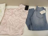 three pairs of jeans sitting on a table next to a cell phone