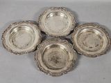 four silverplated dishes are arranged on a white surface