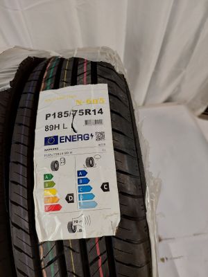 un gros plan d'un pneu posé sur un lit, sur lequel est collé un autocollant
