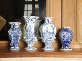 quatre vases bleus et blancs posés sur une étagère devant une fenêtre