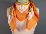an orange scarf on a mannequin torso with a necklace on it