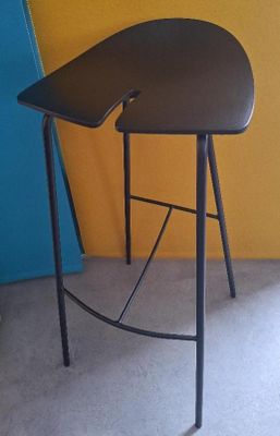 un tabouret noir posé devant un mur jaune et bleu