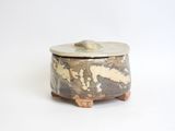 a small pot with a lid sitting on a white surface