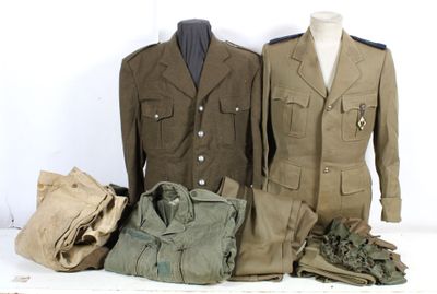 trois uniformes militaires exposés sur une table blanche