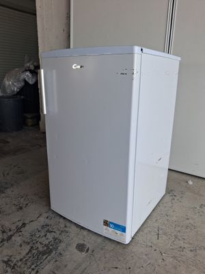 un réfrigérateur blanc posé dans un garage, à côté d'une porte