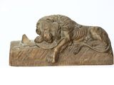 statue d'un lion posé sur un rocher, tenant un oiseau dans sa gueule