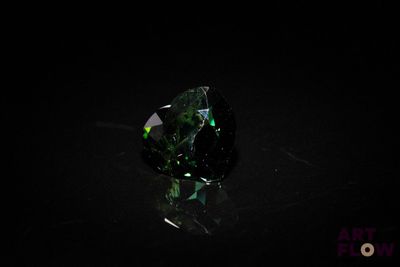 a close up of a green diamond sitting on top of a black surface