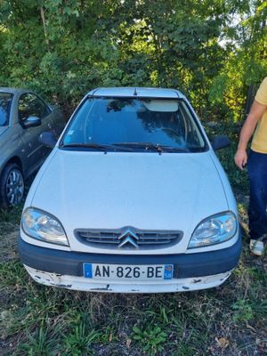 un homme debout à côté d'une voiture garée dans l'herbe
