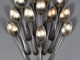 six silver spoons are arranged in a circle on a gray surface
