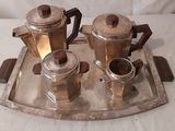 un plateau en argent sur lequel sont posées trois cafetières et une tasse