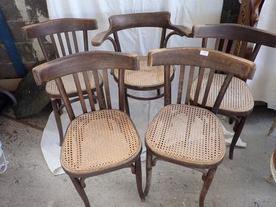 four wooden chairs with woven seats sit in front of a white curtain
