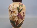 a vase with flowers painted on it sitting on a table