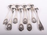 six silver spoons are lined up in a row on a white surface