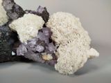 purple and white crystals on a white surface with a gray background