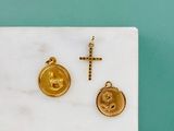 un gros plan d'une croix en or et d'un cachet de cire doré posés sur une dalle de marbre
